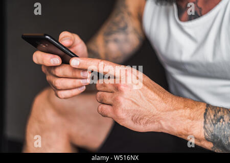 Mans Hände mit Tattoos holding Smartphone Stockfoto