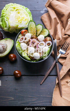 Gemüsesalat mit Eis, Salat, Gurken, Zwiebeln, Tomaten, Mozzarella und Sesamöl. Gesundes Essen. Vertikaler Dampfstoß Stockfoto