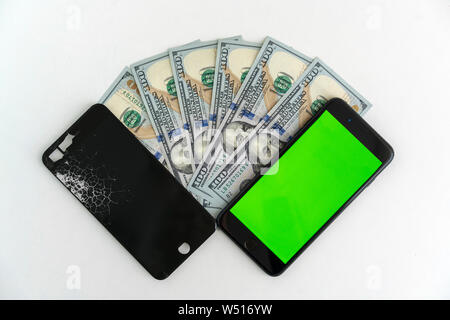 Mobiltelefon mit einer defekten Anzeige auf einem 100-Dollar Bill. Die Zahlung für die Reparatur oder den Austausch des Smartphones. Stockfoto