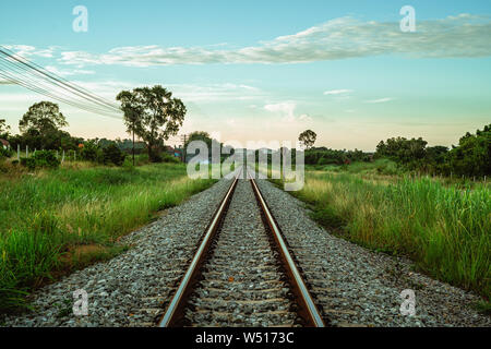 Landschaft der Eisenbahnen geradeaus zwischen grünen ländlichen Felder mit Bäumen Stockfoto