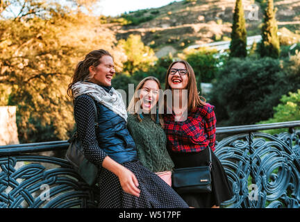 Drei junge Frauen, die auf der Brücke im Park auf Spätsommer Tag lachend Stockfoto