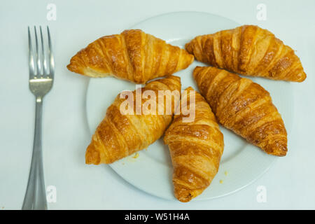 Puffy goldene Croissant auf weiße Platte auf weißem Hintergrund Stockfoto