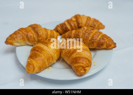 Puffy golden Croissants auf weißem Schild mit weißem Hintergrund Stockfoto