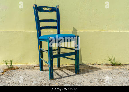 Alten verrotteten blauen Stuhl vor der gelben wand Stockfoto