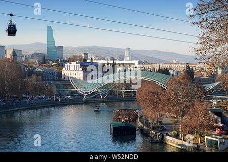 Eine Seilbahn Gondel schwebt über dem Mtkvari River. Im Hintergrund: die Brücke des Friedens von Michele De Lucchi. Der Innenstadt von Tiflis, Georgien, Kaukasus Stockfoto