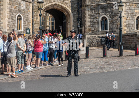 Ein feuerwaffen Polizeiamt steht außerhalb Schloss Windsor mit seinem Maschinengewehr während der Wachwechsel Zeremonie bereit. Stockfoto