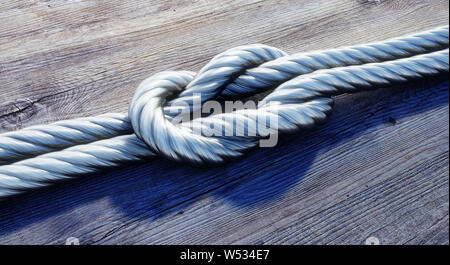 Silver Reef knot oder quadratischen Knoten auf dunklem Holz - 3D-Darstellung Stockfoto