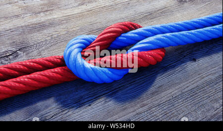 Blau und Rot reffknotens oder quadratischen Knoten auf dunklem Holz - 3D-Darstellung Stockfoto