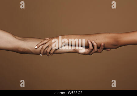 Nahaufnahme von Mann und Frau, Hände halten im Studio. Paar in Liebe Hände halten über braunen Hintergrund. Stockfoto