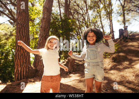 Nette Mädchen Spaß zusammen in den Wald. Kinder tanzen im Park. Stockfoto