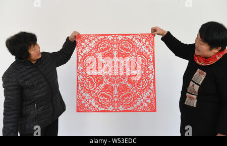 Chinese Folk Künstler Li Yinjie, rechts, zeigt ein Papier-schneiden Artwork mit Schwein den kommenden Frühling Festival oder das Chinesische Neue Jahr (Jahr o zu markieren Stockfoto