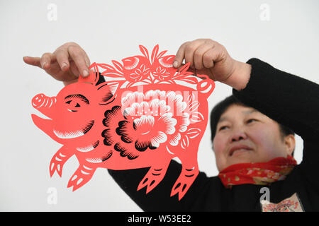 Chinese Folk Künstler Li Yinjie zeigt ein Papier-schneiden Artwork mit Schwein den kommenden Frühling Festival oder das Chinesische Neue Jahr (Jahr des Pi zu markieren Stockfoto