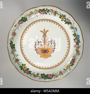 Sauver Teller mit dem Wappen der Familie Zurmegede, Porzellanschale mit gewellter Rand, malte auf der Glasur in Blau, Rot, Rosa, Grün, Gelb, Schwarz und Gold. Auf dem Regal, die Arme der Zurmegede Familie in Gold mit drei miteinander verbundenen Ringen. Der Helm ist eine Krone mit über drei miteinander verbundene Ringe und Pfauenfedern. Die Abdeckung beinhaltet eine Kartusche mit einem rautenförmigen Muster im Stil Louis XIV zusammen mit Blättern und eine Reihe von Perlen auf beiden Seiten. Eine Speerspitze Grenze an der Wand. Am Rande einer Dekoration von floralen Ranken und Bambus. Die Platte wurde unterbrochen. Waffe Porzellan mit Emaille Stockfoto