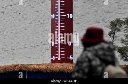 Fußgänger Spaziergang, vorbei an einem riesigen Thermometer mit Anzeige der aktuellen Außentemperatur in Chongqing, China, 4. Januar 2019. Stockfoto