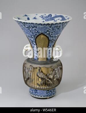 Trompetenförmigen beakervase mit einem Metall Vogelkäfig, Trompetenförmigen Porzellan Vase, in unterglasur Blau und auf der Emaille Rot, Schwarz und Gold bemalt. An der Wand ein Muster der Päonien durch vier unterbrochen, versenkt, blattförmige Boxen mit einem Hakenkreuz oder körnige Muster in vergoldeten Papier Pappmaché. Ein Ohr in Form von einem Elefanten in zwei Fächern. Ein metall Vogel Käfig hat unter diesen Ohren, um die Vase gestellt, ruht auf lackierten Holz- kanten. Unterhalb der Oberkante eine Band mit vier ruyi Motive der vergoldeten Papier Pappmaché. Steine, Äste und ein Paar von männlichen und weiblichen grünen Fasan (Phasianus versicolor Stockfoto