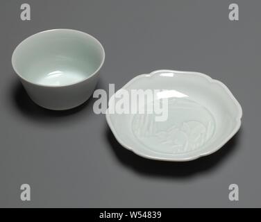 Glockenförmige Tasse und Untertasse mit zwei Hasen und der Mond in der Entlastung, glockenförmige Kelch und ein scalloped Porzellanschale mit einem celadon grüne Glasur. Auf der Platte der Untertasse geprägte zwei Hasen in einer Landschaft unter dem Mond zwischen den Wolken. An der Unterseite des Kopfes nur der Mond zwischen den Wolken. Auf der Unterseite markiert. Monochromen., Masato Imaizumi, Japan, C. 2002, Porzellan (Material), Glasur, Verglasung, h 5,3 cm h 4,3 cm, d 7,8 cm, d 3,9 cm h 2,3 cm, d 11,2 cm, d 5,8 cm Stockfoto