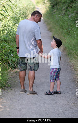 Ein Junge und Grand Elternteil teilen einen Moment Spaß, während Sie auf einem Naturlehrpfad Spaziergang auf dem Land Stockfoto