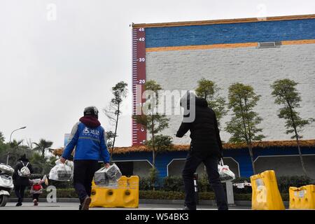 Fußgänger Spaziergang, vorbei an einem riesigen Thermometer mit Anzeige der aktuellen Außentemperatur in Chongqing, China, 4. Januar 2019. Stockfoto