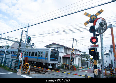 Touristen nehmen Fotos als einen Zug auf der Enoden Linie fährt hinter dem Bahnübergang gegen die Skyline von Sea Scape in Kamakura, Kanagawa, Japan, 2. Stockfoto