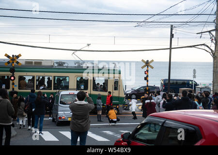 Touristen nehmen Fotos als einen Zug auf der Enoden Linie fährt hinter dem Bahnübergang gegen die Skyline von Sea Scape in Kamakura, Kanagawa, Japan, 2. Stockfoto