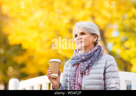 Ältere Frau trinkt Kaffee im Herbst Park Stockfoto