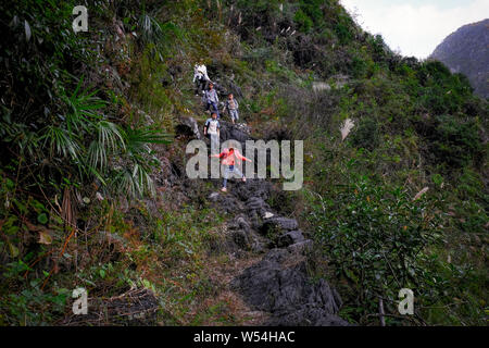 Kinder eine Leiter aus Stöcke und Zweige auf einer Klippe zu gehen zwischen den Bergen in Nongli Dorf zur Schule, Bansheng Stadt, dahua Yao EIN Stockfoto