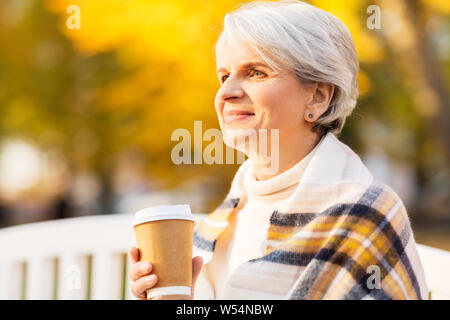 Ältere Frau trinkt Kaffee im Herbst Park Stockfoto