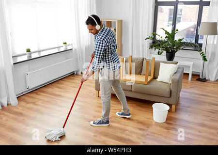 Mann in Kopfhörer mit Mop Reinigung Boden zu Hause Stockfoto