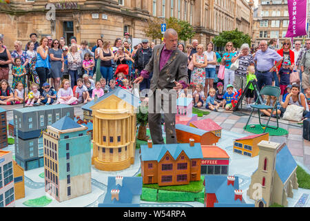 Glasgow, UK. 26. Juli 2019. Glasgow's jährliche grösste Festival der freien Straße Unterhaltung zieht Tausende von Touristen und Zuschauer mit der Merchant City District Street Theater, mime-Performances, Musik und Puppenspiel über einen dreitägigen Wochenende zu genießen. Akteure aus den Whalley Range All Stars Straßentheater aus Manchester führen Sie das Spiel "Alle Tage" Credit: Findlay/Alamy leben Nachrichten Stockfoto