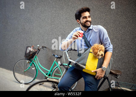 Schön lächelnden Mann sitzt auf einem Fahrrad auf der Straße und trinken Kaffee. Stockfoto