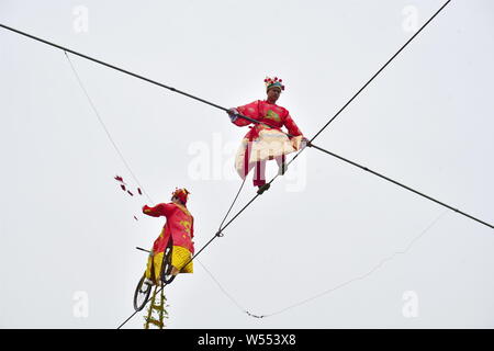 Chinesische Akrobatik Schauspieler verkleidet als der Gott des Reichtums einer Gratwanderung in einem Park am fünften Tag der chinesische Mondjahr oder Frühlingsfest brave Stockfoto