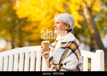 Ältere Frau trinkt Kaffee im Herbst Park Stockfoto