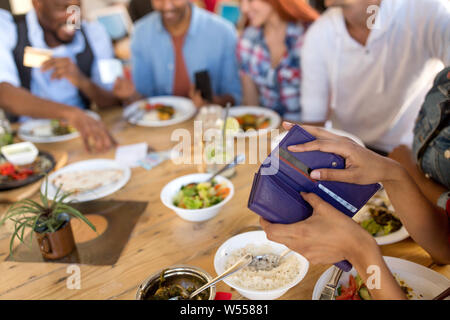 Weibliche Hände, die Brieftasche im Restaurant Stockfoto