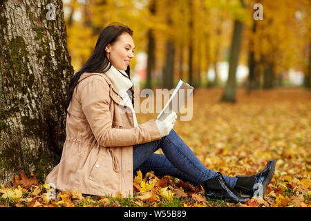 Frau liest Buch im Herbst Park Stockfoto