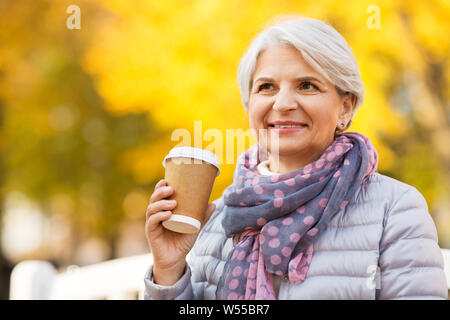 Ältere Frau trinkt Kaffee im Herbst Park Stockfoto