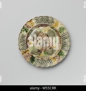 Platte von bunten Hard- abgefeuert, Steingut, Staffordshire, Platte von bunten Hard- feuerte Steingut. Die Grenze ist mit Verzierung, mit zwei symmetrischen floralen Mustern durchsetzt geprägte nebeneinander platziert. Die gekerbte Kante ist auf der Innenseite mit Voluten und Blattmotiven dekoriert. Die Platte ist mit eine gefleckte führen in Mangan Glasur, Grün, Grau und Gelb. Der Rücken ist in Mangan punktiert und hat einen Fuß Flanke, anonym, England, C. 1750 - C. 1780, Steingut, führen Glasur, h 1,6 cm x T 19,3 cm Stockfoto