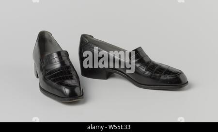 Schwarz Leder slip-on mit Krokoleder schwarz Zunge, Links schwarz Leder slip-on mit Krokoleder schwarz Zunge. Modell mit geraden Nase und flachem Absatz. Schwarz Leder Seitenteile erstrecken sich auf die Nase, die hat zwei Nähte. Unter dem Rist über die Zunge ein Band aus schwarzem Leder. Graues Innenfutter aus Leder, mit Ausnahme der Zunge auf dem Spann: schwarz gesäumt. Innensohle mit goldenen Drucken. Adresse (auf der Innensohle): A. VAN GOETHEM 15 RUE DE NAMUR/PRES LA PLACE ROYALE BRUXELLES., A. Van Goethem, Brüssel, C. 1960 - C. 1970, Love, l 26 cm x B 8,5 cm x H 10 cm Stockfoto