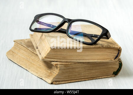 Brillen auf Abgelegte Bücher auf weißem Holz- Hintergrund platziert Stockfoto