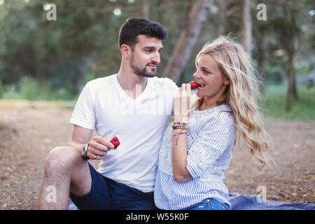 Glückliches junges Paar essen Erdbeere auf Picknick in der Natur Stockfoto