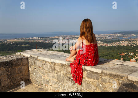 Das Mädchen sitzt auf der Festungsmauer. Stockfoto