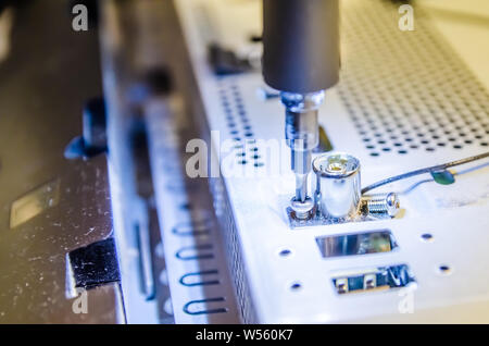 Mann unspins die Abdeckung des Steuergeräts der Monoblock mit einem Schraubendreher mit Hintergrundbeleuchtung Stockfoto