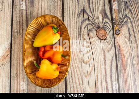 Paprika in einem Weidenkorb auf einem Holztisch. Herbst erntedankfest Tag. Stockfoto