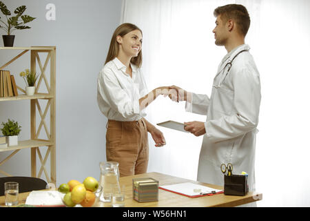Die junge Frau, die ein Arzt für eine Ernährung Empfehlungen. Männliche Ernährungssachversta5ndiger bilden eine gesunde Diät Plan bis zum Patienten. Konzept der gesunden Lebensweise und Ernährung, Medizin und Behandlung. Stockfoto