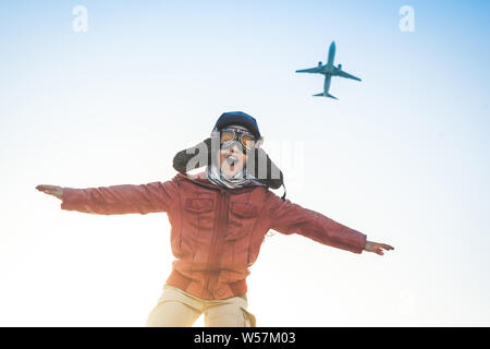 Schöner Junge spielt gerne Rennen mit dem Flugzeug freudig vorgibt, verkleidet als vintage Aviation Pilot Hut, Brille Maske Leder Jacke Stockfoto