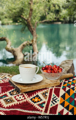 Kaffee und Kirschen außerhalb Schneidebrett in der Natur Stockfoto