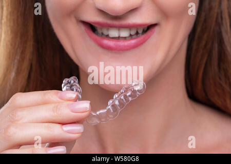 Nahaufnahme von einer Frau Hand Transparent Ausrichter in Zähne Stockfoto