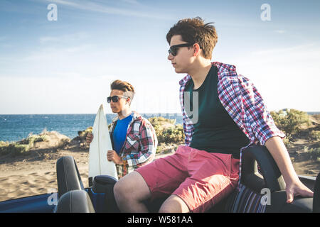 Zwei junge Teenager gerne beste Freunde suchen Die hotizon mit Surfbrett. Profil Porträt von zwei glücklichen jungen außerhalb. Konzept der Freundschaft und Stockfoto