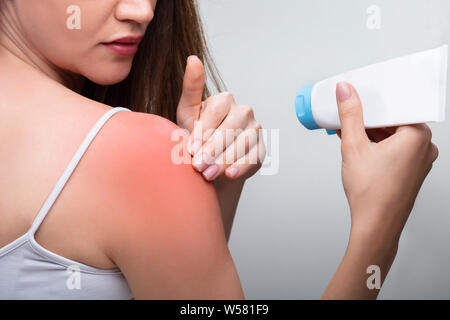 Nahaufnahme einer jungen Frau die Hand Creme auf Ihrer Schulter Stockfoto