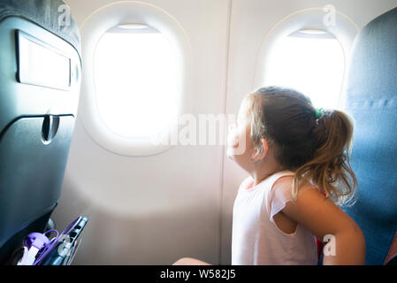 Süße kleine Mädchen Reisen in Flugzeug Blick durch Fenster Stockfoto