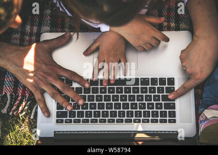 Glückliche Familie mit Laptop Computer zusammen in den Garten im Sommer. Kid Bildung und Familie Tätigkeiten, die Kommunikation zwischen den Generationen con Stockfoto